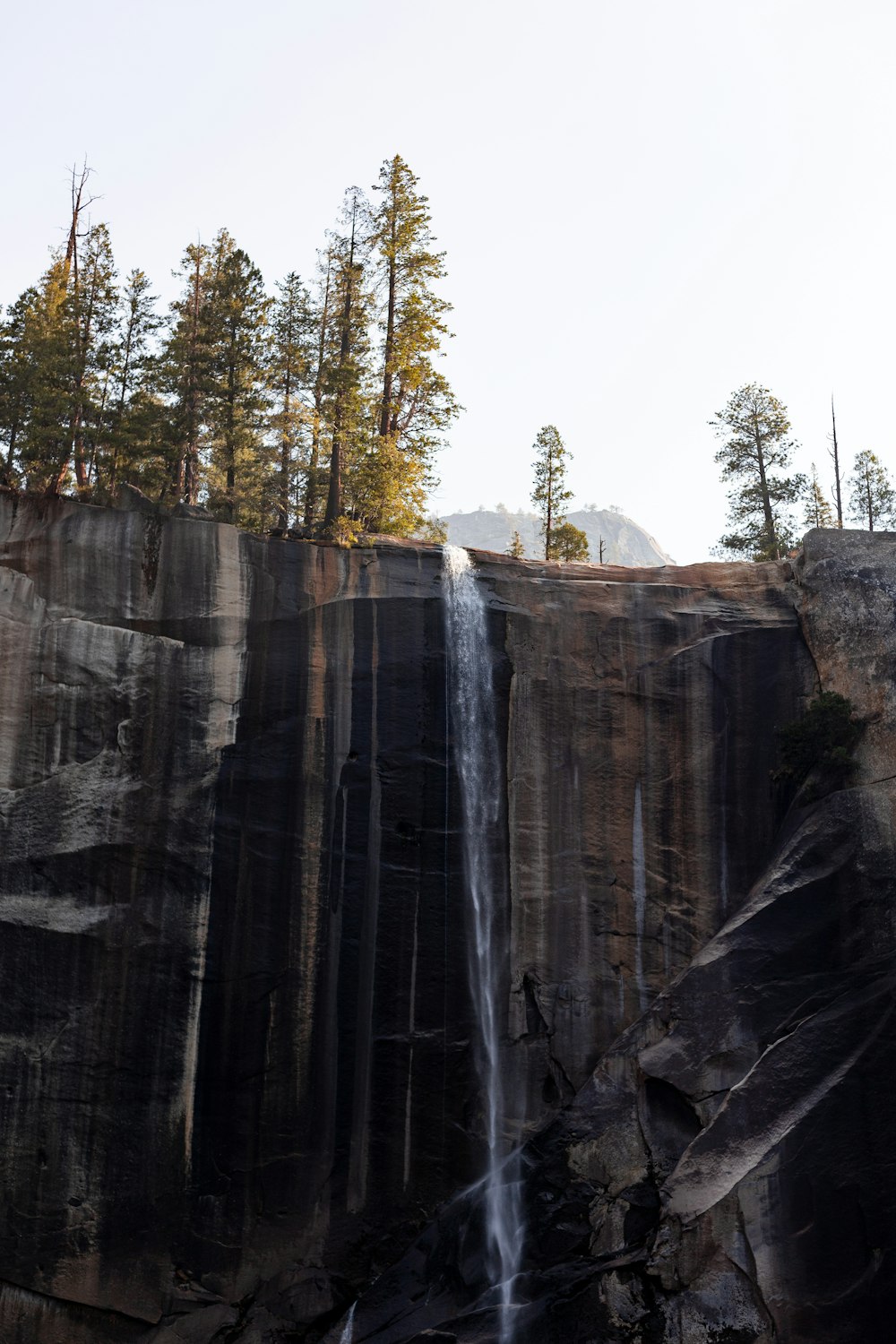 a tall waterfall with a forest in the background