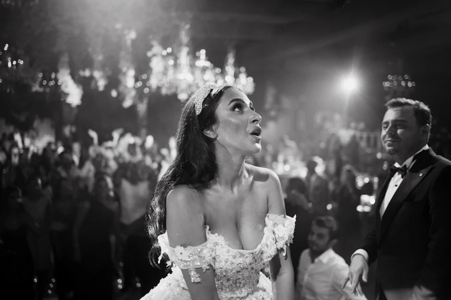 Bride dancing in the middle of the crowd at the reception, black and white