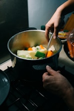 Close-up of hands gently stirring a slow-cooked ancestral stew in a rustic clay pot.
