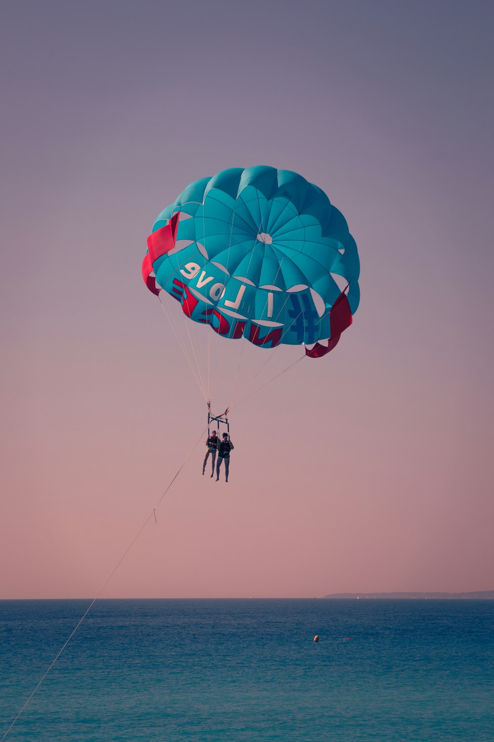 um par de pessoas parasailing sobre o oceano