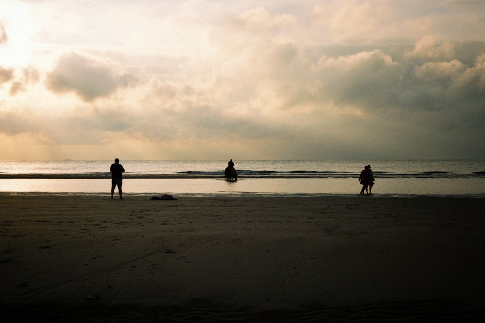 a group of people standing on top of a sandy beach