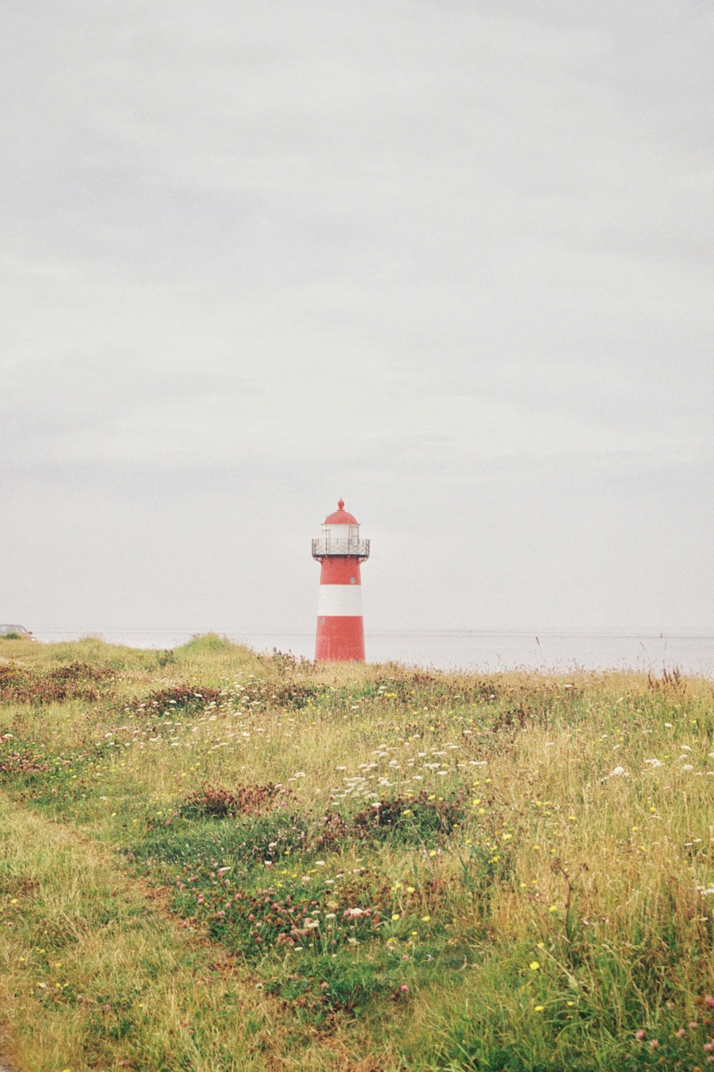 a red and white lighthouse sitting on top of a lush green field