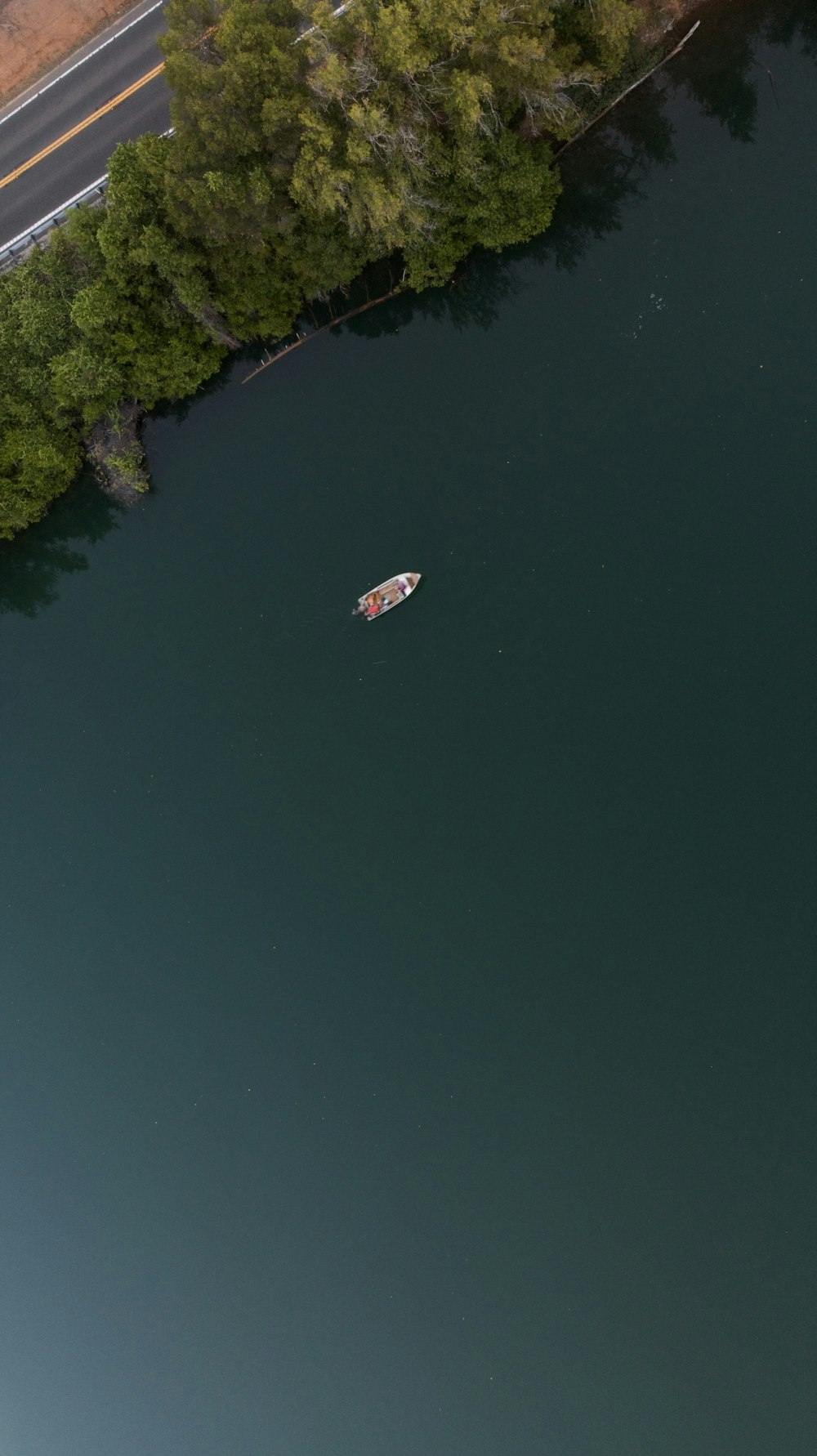 a boat floating on top of a lake next to a forest