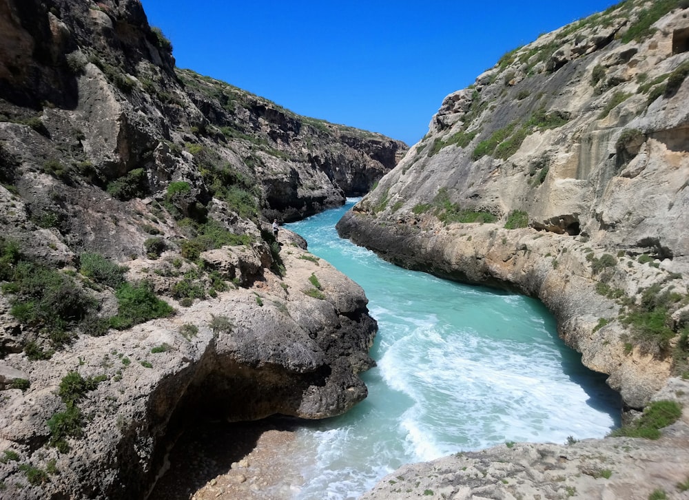 a river running through a rocky canyon next to a cliff