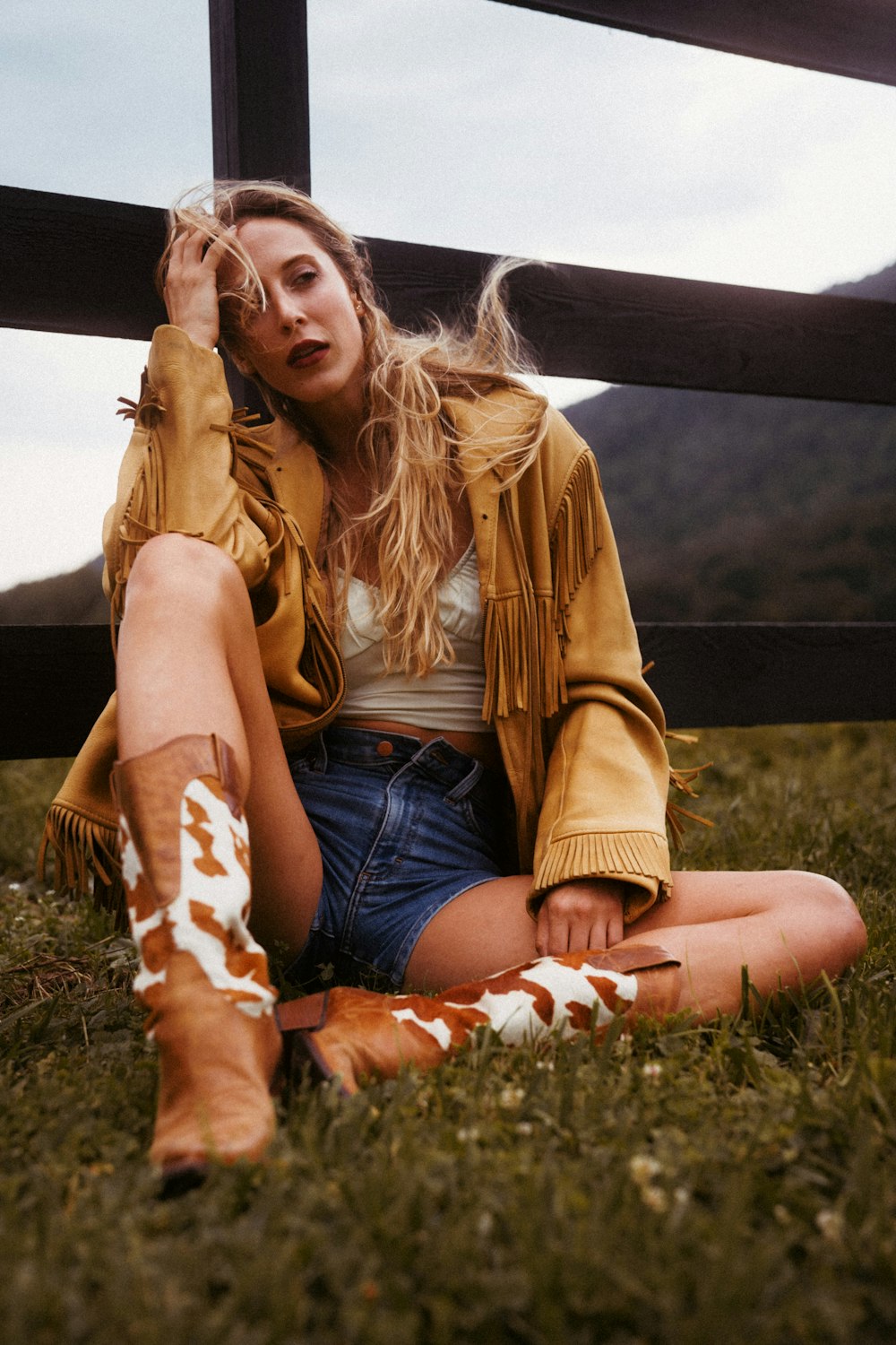 a woman sitting on the ground next to a fence