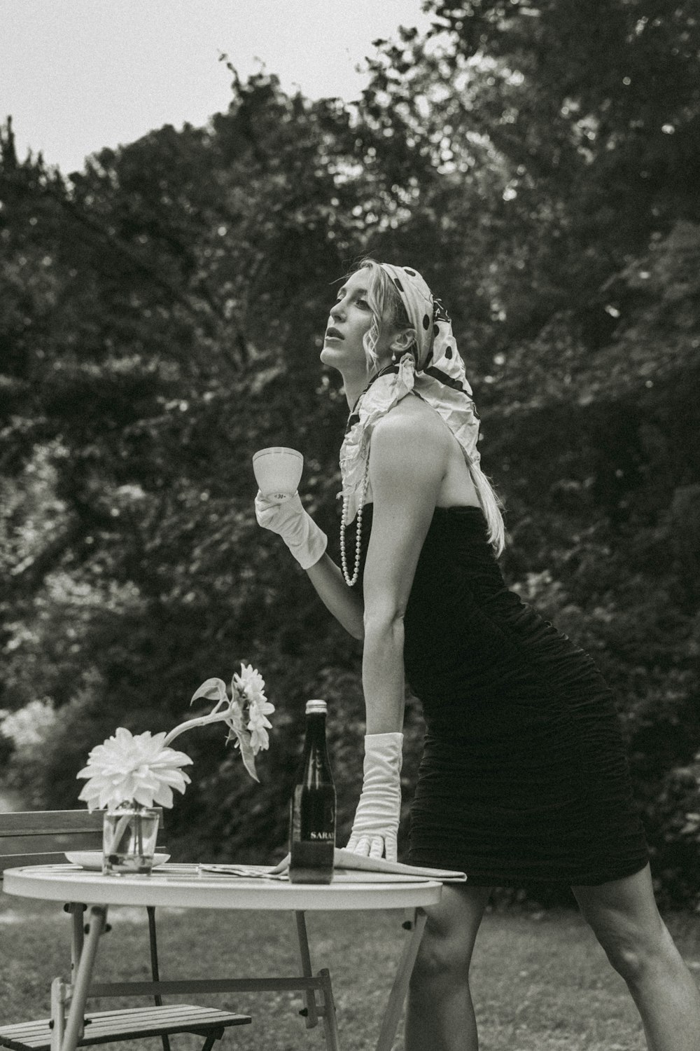 a woman standing at a table with a bottle of wine