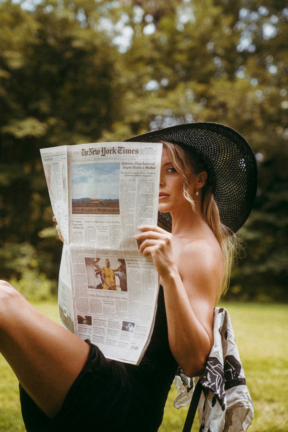 草の上に座って新聞を読む女性