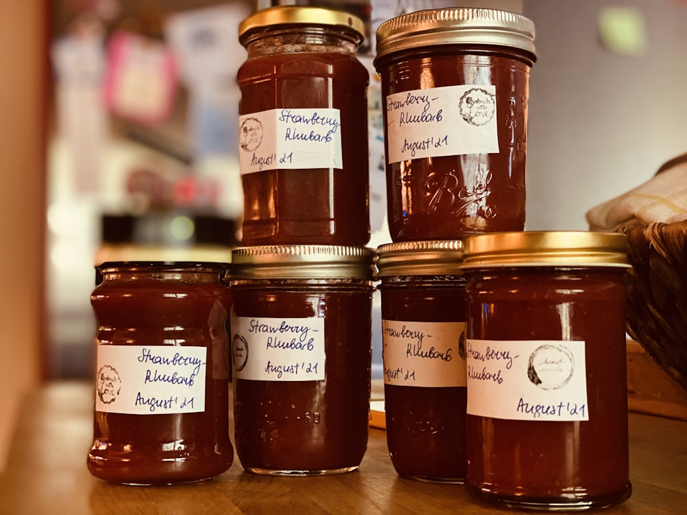 a group of jars filled with jam sitting on top of a wooden table