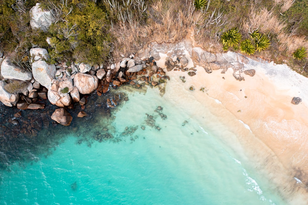 an aerial view of a beach with rocks and water