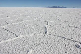 a vast expanse of white snow with mountains in the distance