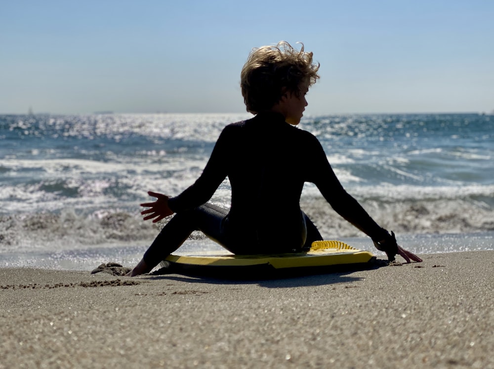 a person sitting on a surfboard on the beach