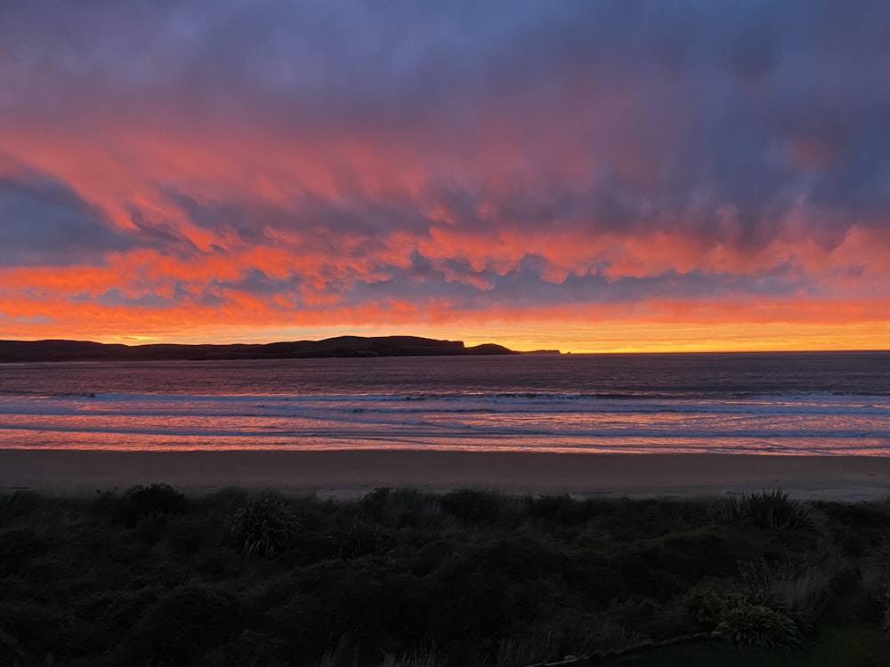 a beautiful sunset over the ocean with a small island in the distance