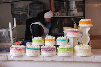 a woman standing in front of a table filled with cakes
