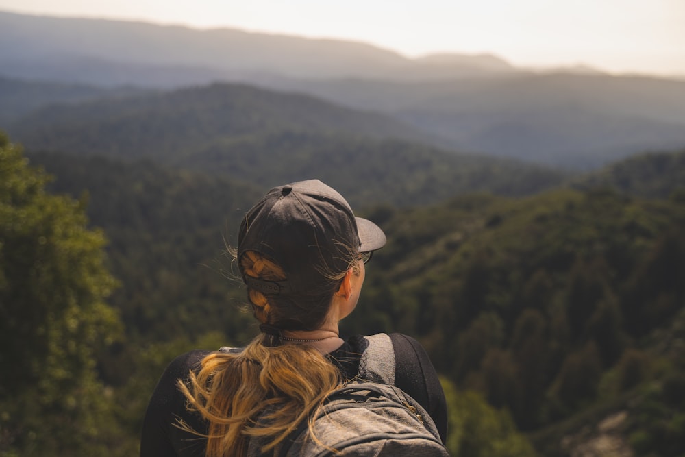 a woman with a backpack looking at the mountains