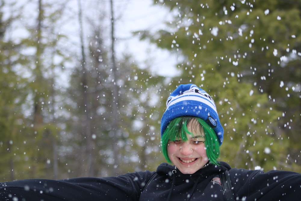 a young boy with green hair wearing a blue and white hat