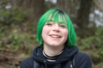 a girl with green hair and a black hoodie