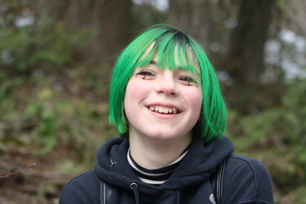 uma menina com cabelo verde e um moletom preto