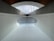 A modern architectural structure featuring a large arched ceiling with geometric patterns. The ceiling is primarily white with a subtle texture, and there is a row of windows at the top allowing natural light to illuminate the space. The design is symmetrical, creating a sense of depth and openness.
