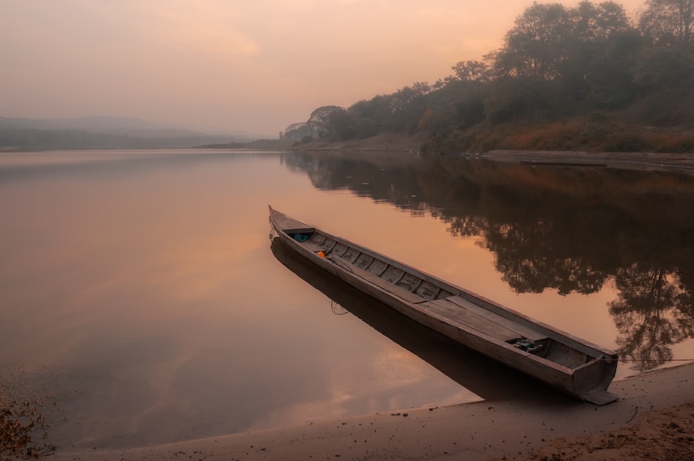 a boat sitting on the shore of a lake