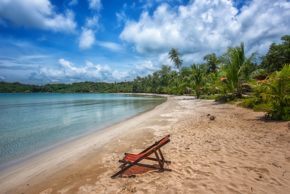 a wooden chair sitting on top of a sandy beach