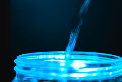 Close-up of clear deionized water being poured into a laboratory container.