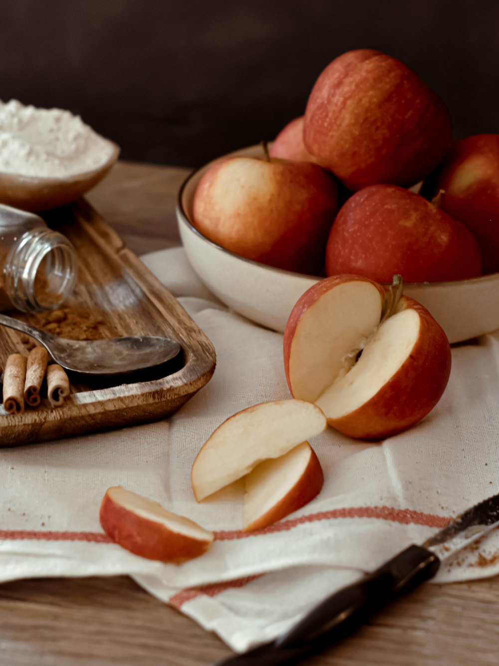 a wooden cutting board topped with apples next to a bowl of oatmeal