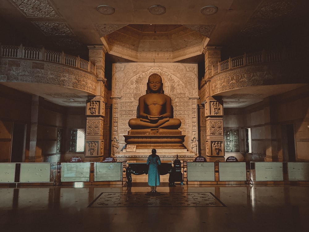 two people standing in front of a buddha statue