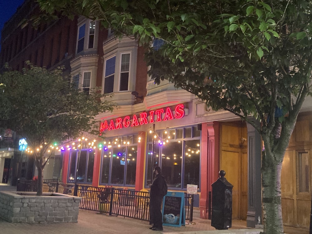 a person standing outside of a restaurant at night