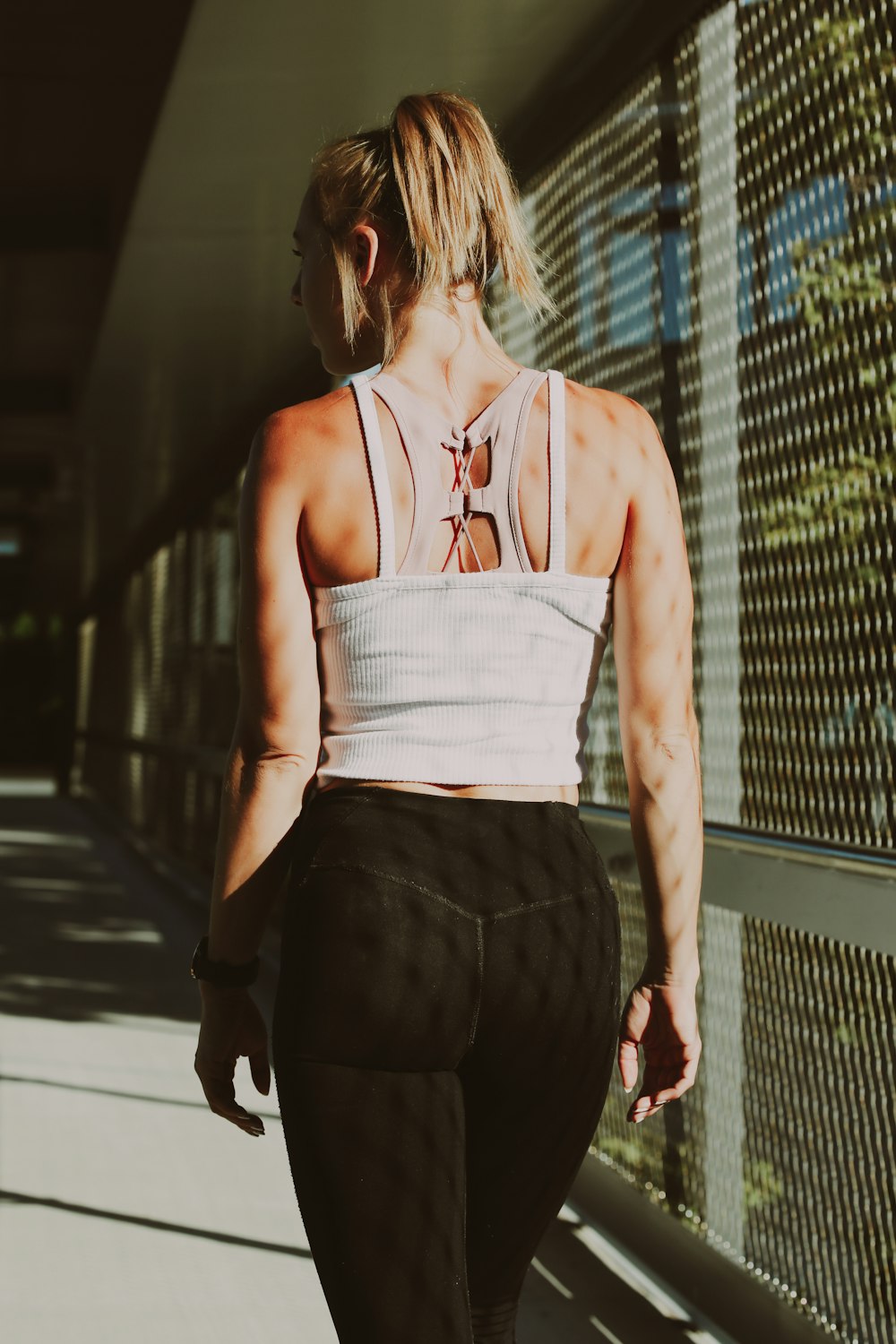 a woman walking down a sidewalk with her back to the camera