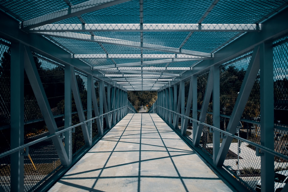 a walkway with a metal frame and a blue roof
