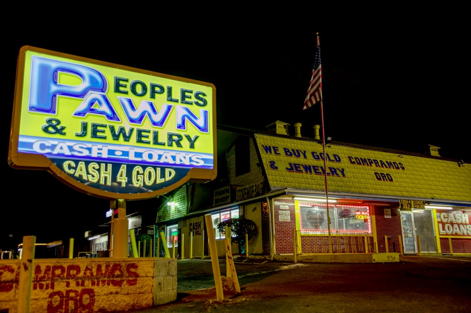 A sign outside of a pawn shop lit up during the night 