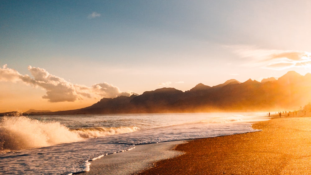 the sun is setting over a beach with waves