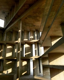 Complex geometric structure of concrete walls with rectangular and diagonal lines. Light filters through the gaps, creating a pattern of shadows and highlights on the surfaces.