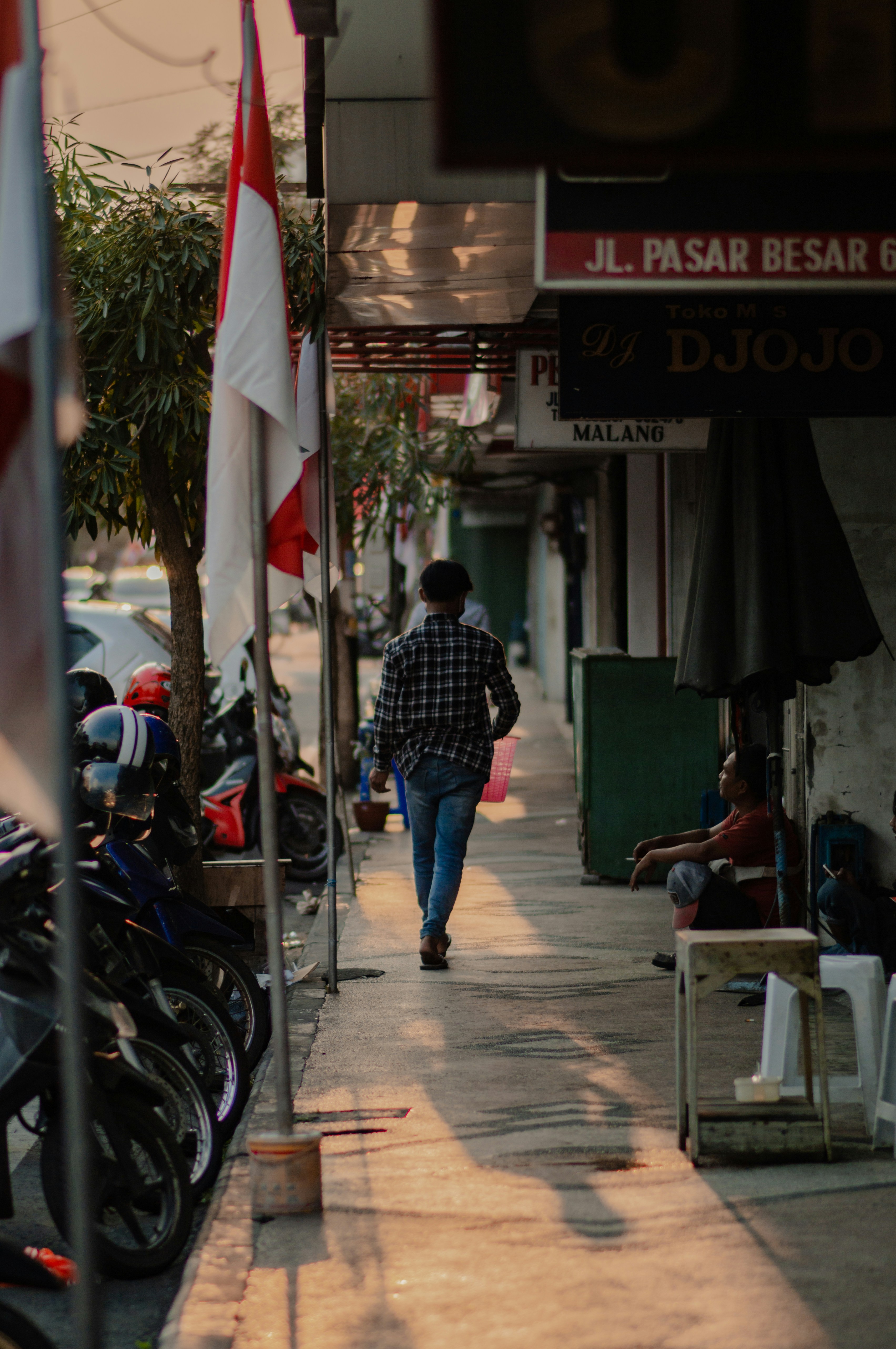 a man walking down a sidewalk next to parked motorcycles