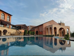 A modern luxury villa with a sparkling pool overlooking the Mediterranean Sea at sunset.