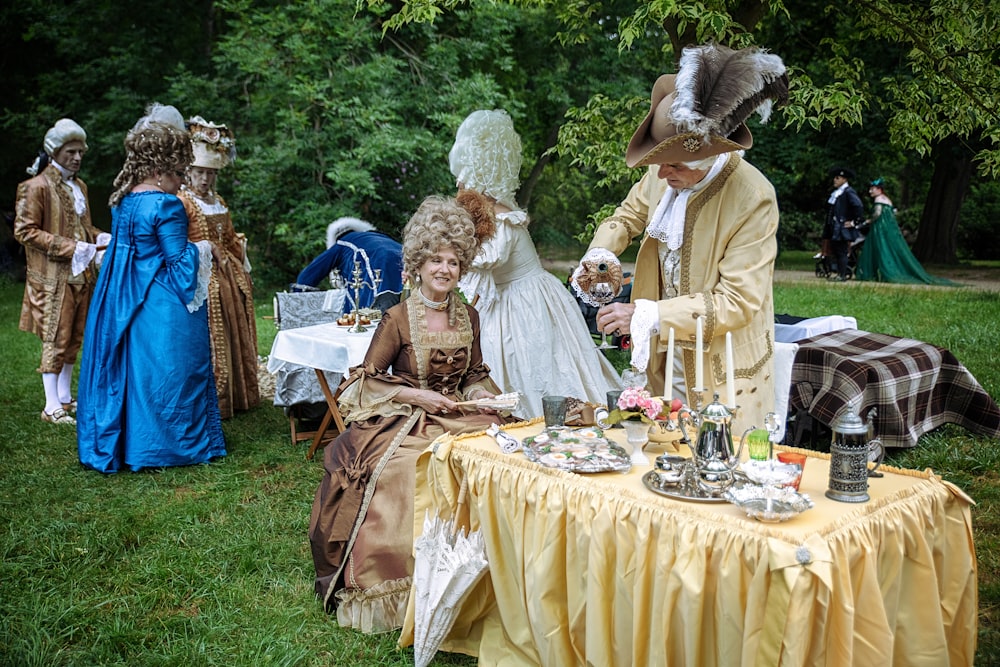 a group of people dressed in period costumes at a tea party