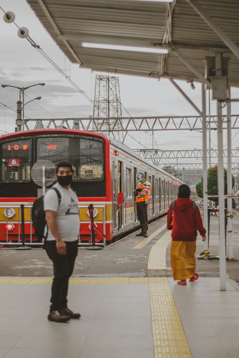 a man standing in front of a red and yellow train