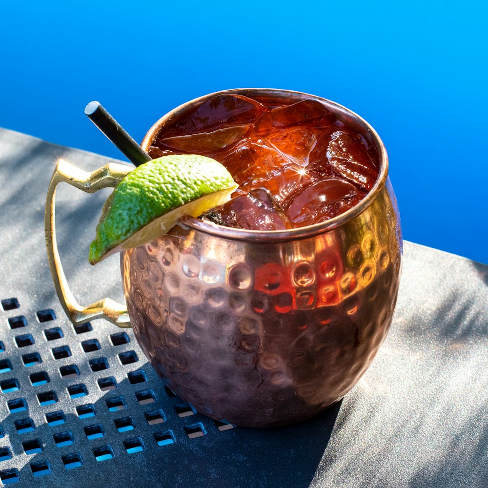 a metal cup filled with a drink on top of a table