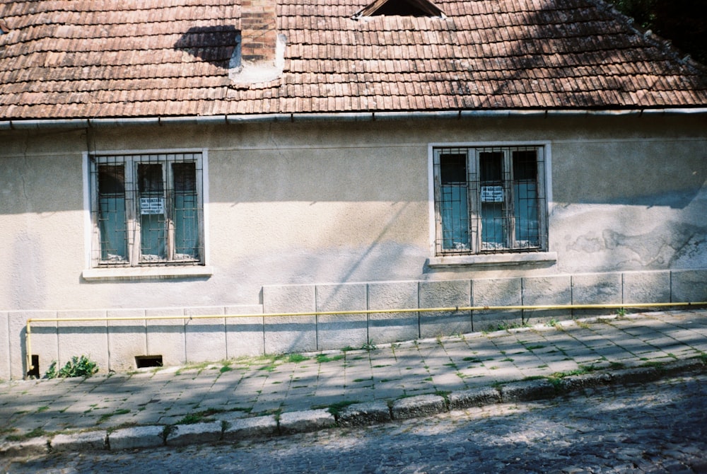 an old building with two windows and a fence in front of it
