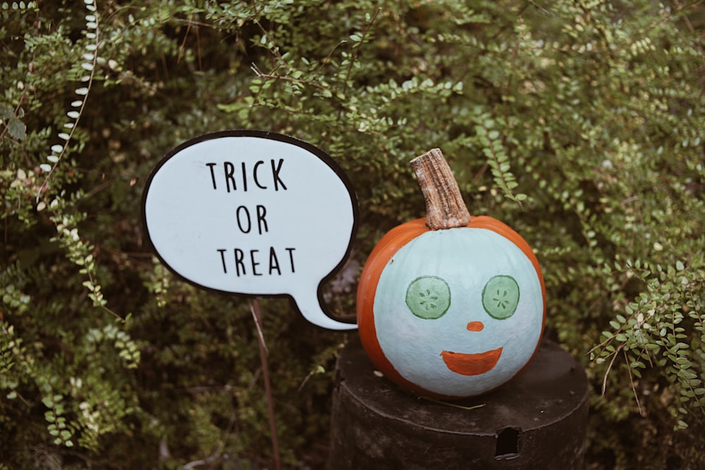 a trick or treat pumpkin sitting on top of a tree stump