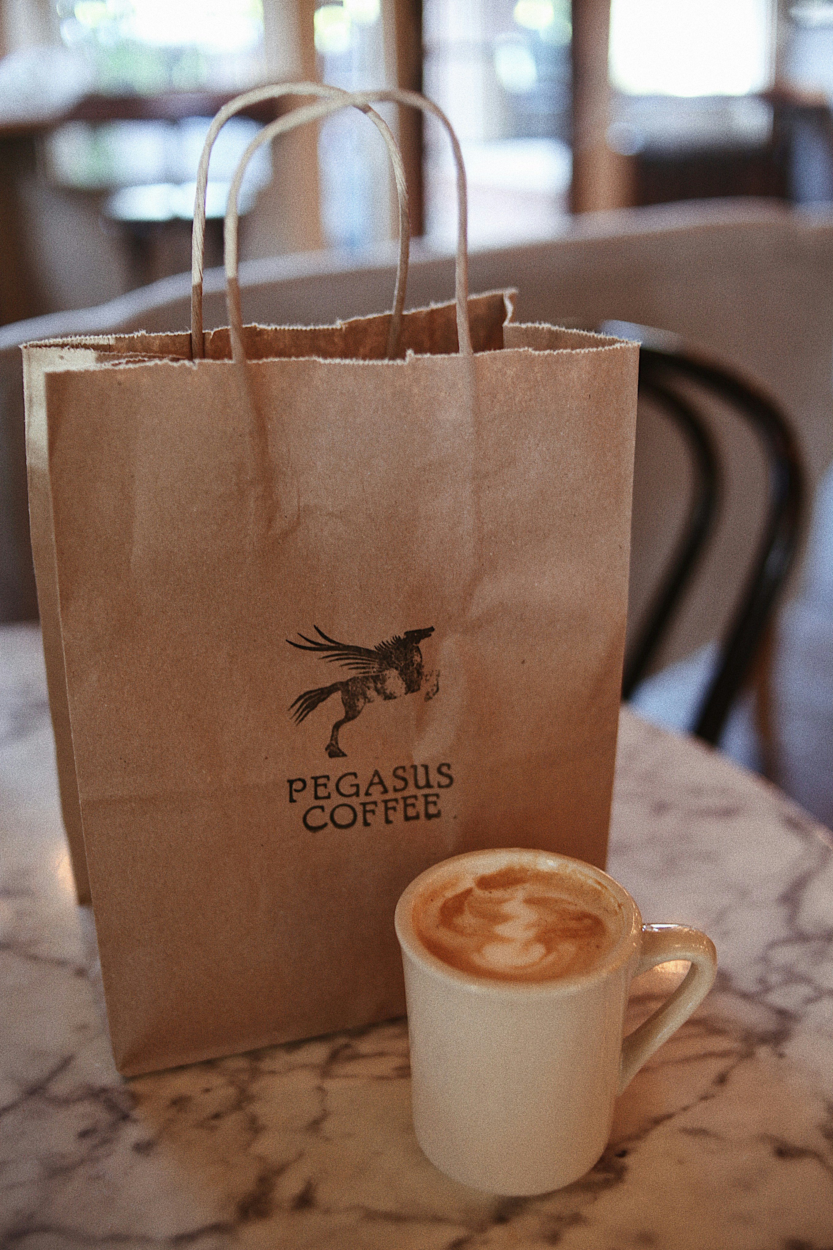 A cup of coffee sitting next to a paper bag photo – Free Coffee cup ...