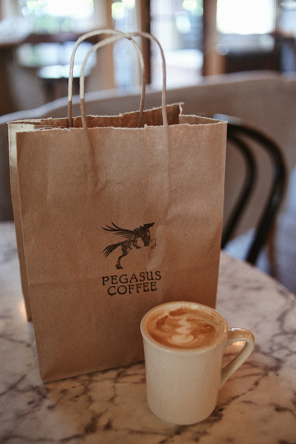 a cup of coffee sitting next to a paper bag