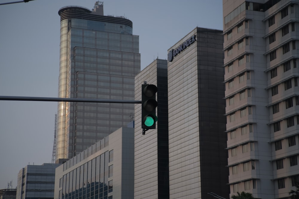 a green traffic light in front of tall buildings