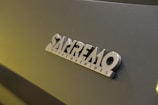Close-up view of a 'Sanremo Coffee Machines' logo on a dark surface.