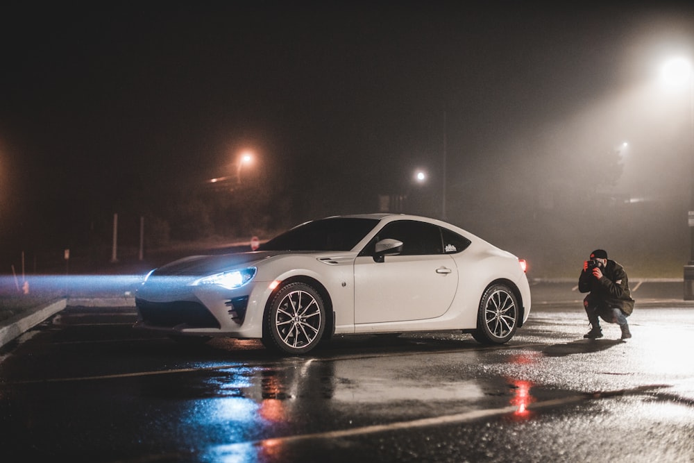 a white sports car parked in a parking lot at night