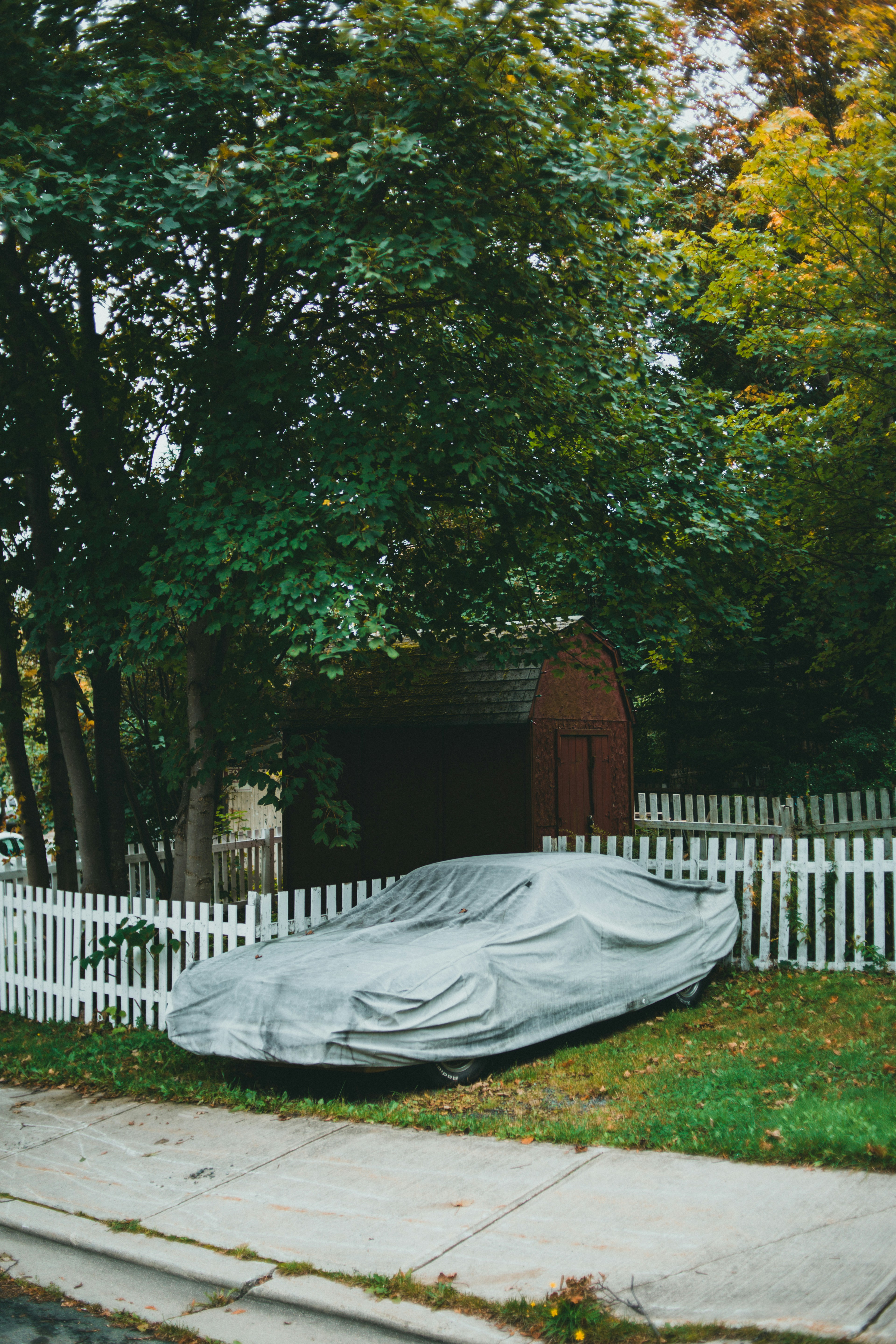 a car covered in a tarp sitting on the side of a road