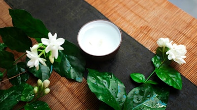 A small earthen bowl filled with cold-pressed sesame oil surrounded by sesame seeds on a beige linen cloth.