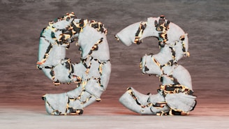 Two large numbers, nine and three, appear to be made of stone with glowing fissures running through them, creating a striking visual effect. The surface is rough, and the contrasting bright orange and black colors highlight the cracks, against a muted background.