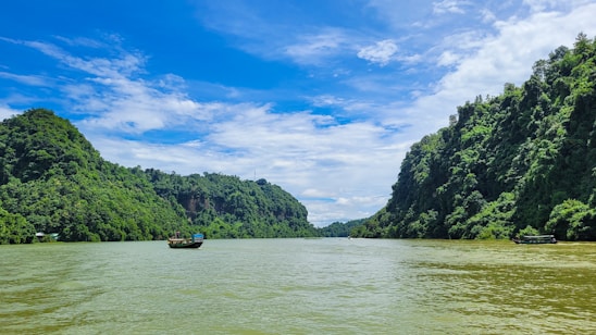 A serene view of a river with boats and lush greenery along the banks.