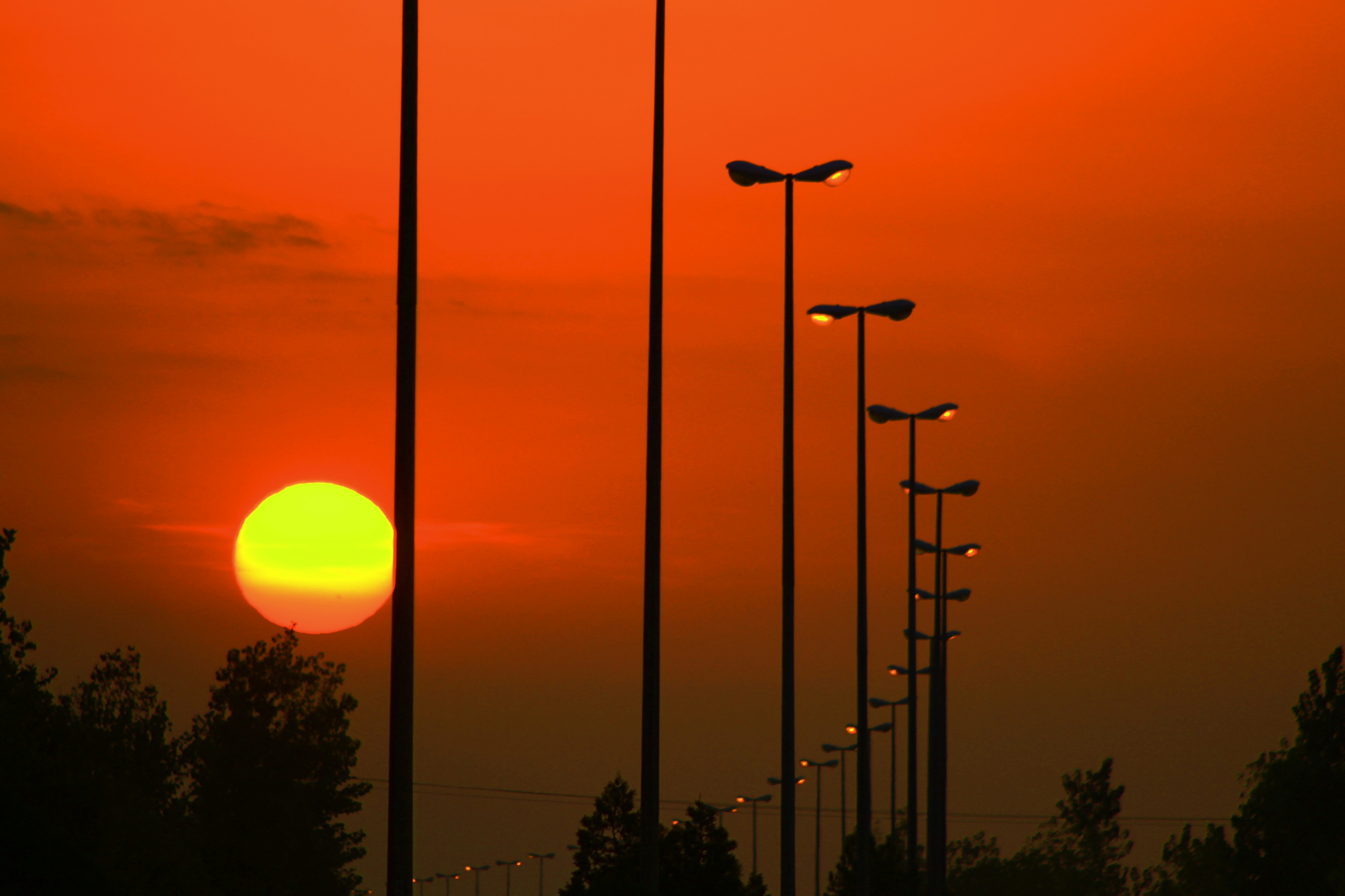 a row of street lights with the sun setting in the background